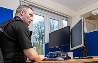 Cop looking at computer monitors