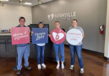 NashComm staff at Nashville Rescue Mission holding signs of support.